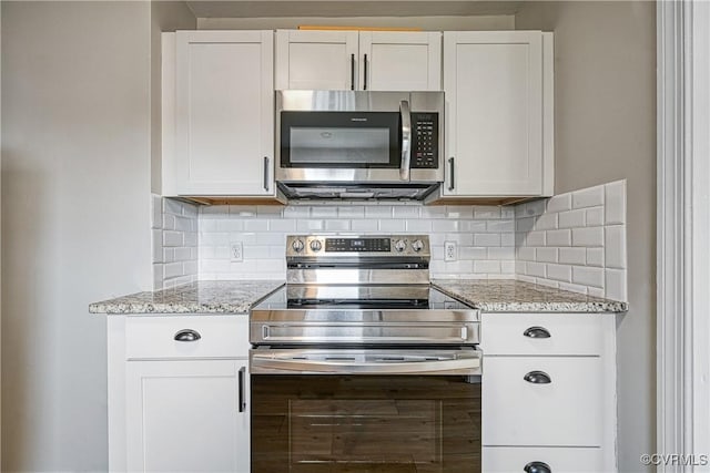 kitchen featuring white cabinetry, light stone countertops, tasteful backsplash, and appliances with stainless steel finishes