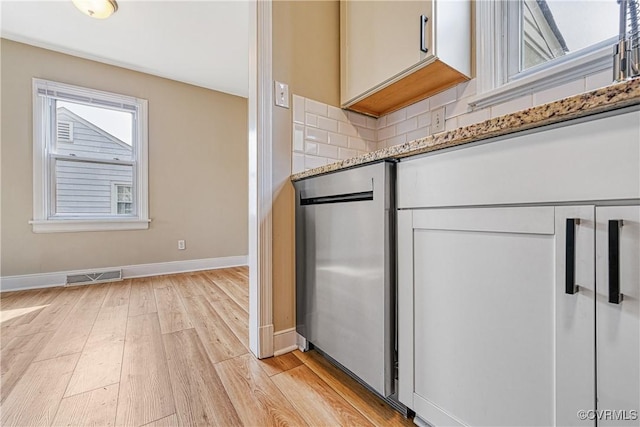 kitchen featuring decorative backsplash, light wood-style flooring, visible vents, and a wealth of natural light