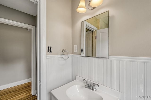 bathroom featuring wainscoting, wood finished floors, and a sink