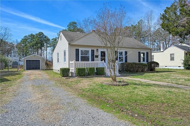 view of front facade with a detached garage, a front lawn, a porch, an outbuilding, and driveway