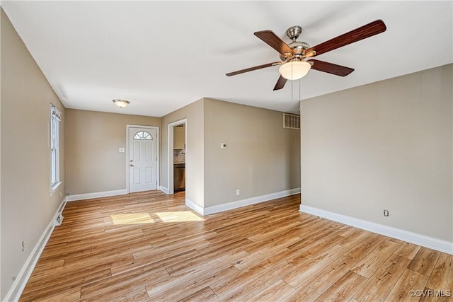 empty room featuring a ceiling fan, baseboards, visible vents, and light wood finished floors