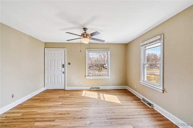 spare room with visible vents, light wood-style flooring, a ceiling fan, and baseboards