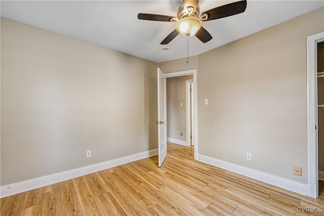 unfurnished room with light wood-style flooring, a ceiling fan, and baseboards