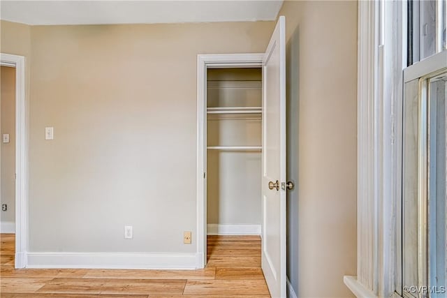 unfurnished bedroom featuring light wood-style flooring, baseboards, and a closet