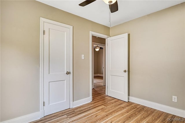 unfurnished bedroom with light wood-style flooring, a ceiling fan, and baseboards