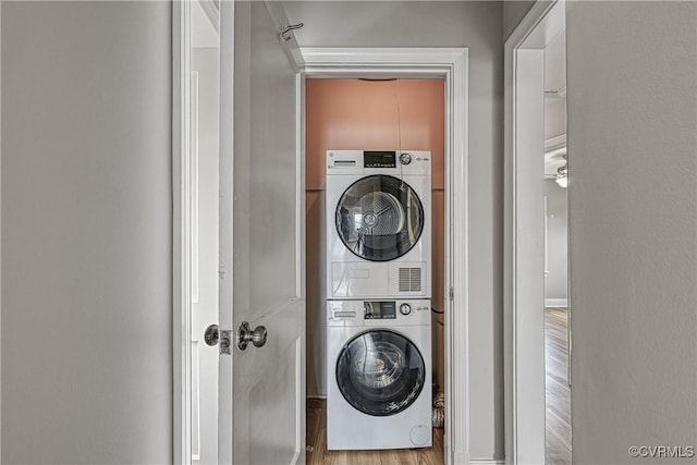 washroom with laundry area, stacked washer / drying machine, and wood finished floors