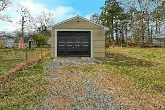 detached garage featuring driveway and fence