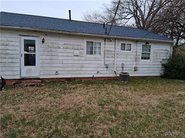 rear view of house featuring a yard, roof with shingles, and central AC