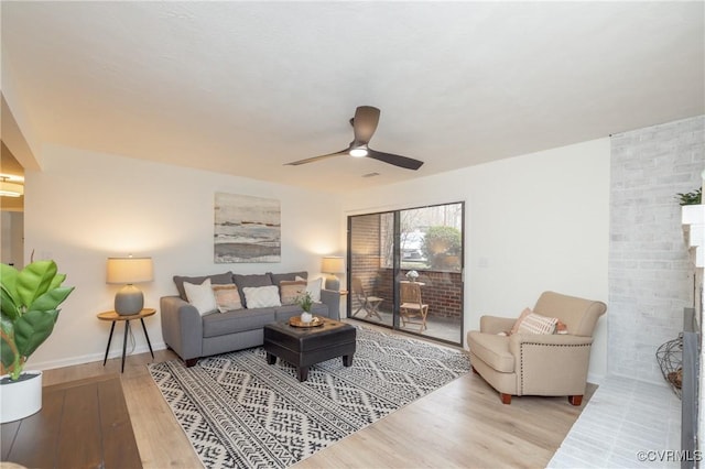 living room with ceiling fan, baseboards, wood finished floors, and a fireplace