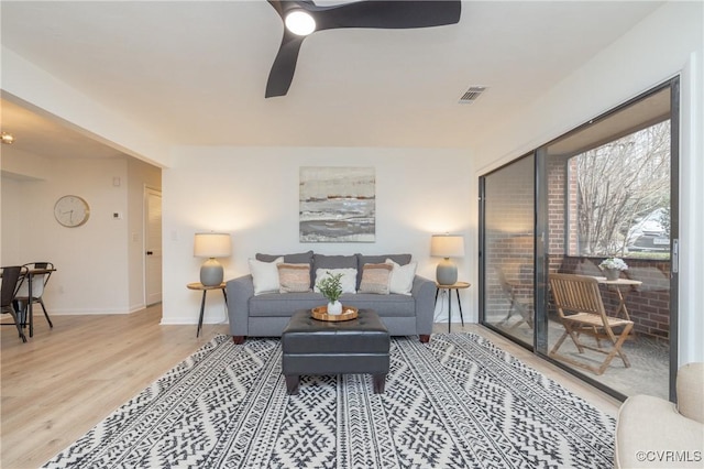 living area featuring ceiling fan, visible vents, baseboards, and wood finished floors