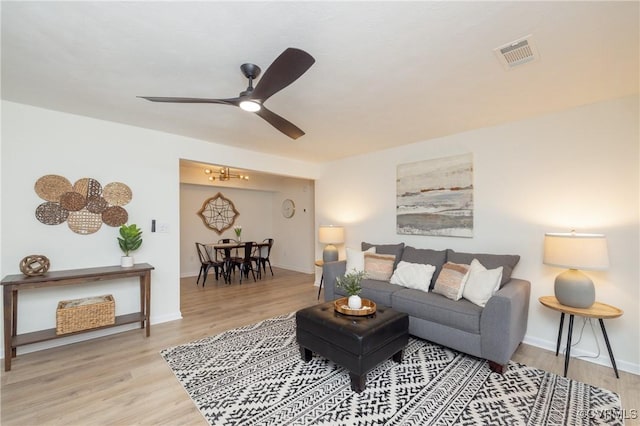 living room with a ceiling fan, wood finished floors, visible vents, and baseboards