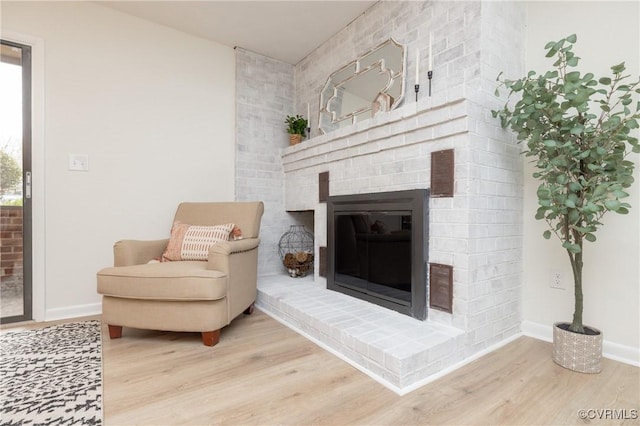 sitting room with visible vents, a brick fireplace, wood finished floors, and baseboards