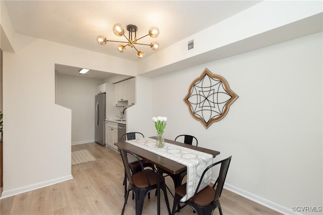 dining room featuring a notable chandelier, visible vents, baseboards, and light wood finished floors