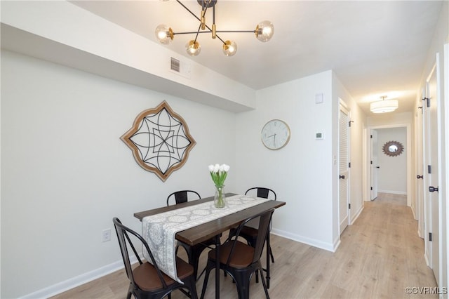 dining area with visible vents, baseboards, a notable chandelier, and light wood-style flooring