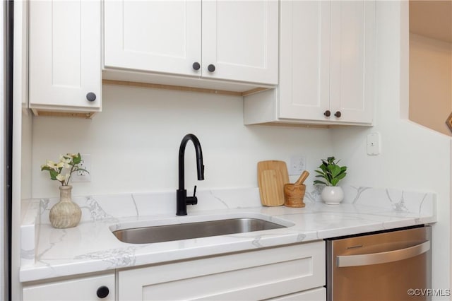 kitchen with stainless steel dishwasher, light stone countertops, white cabinetry, and a sink