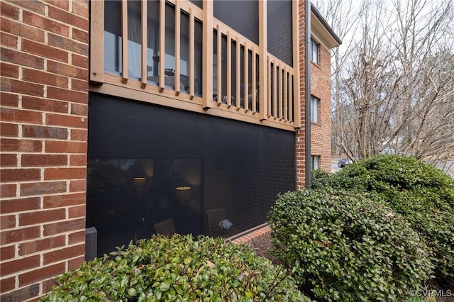 view of property exterior with brick siding and a balcony