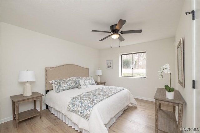 bedroom featuring light wood-style flooring, a ceiling fan, and baseboards