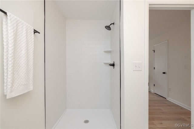 bathroom featuring wood finished floors and a tile shower