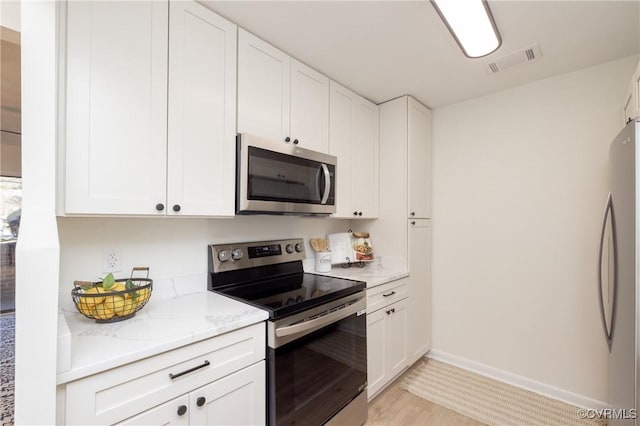 kitchen featuring visible vents, appliances with stainless steel finishes, white cabinetry, and light stone countertops