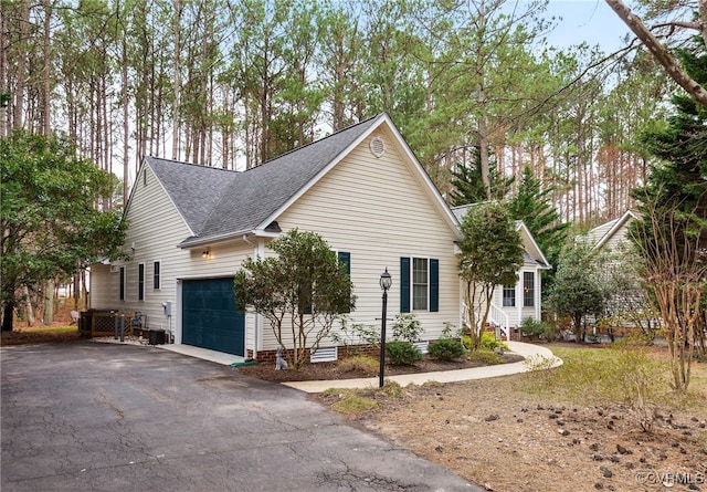 view of front of property featuring aphalt driveway, a shingled roof, and a garage