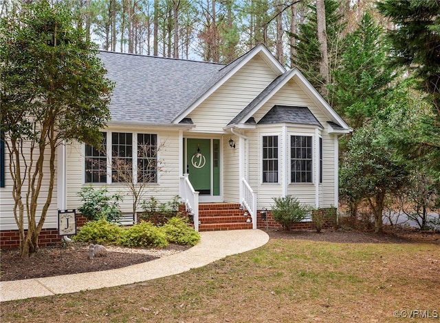 view of front of property featuring entry steps, a front lawn, and roof with shingles