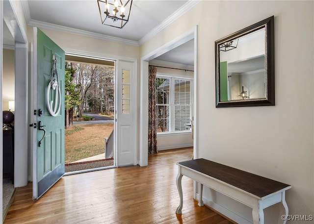 entrance foyer with wood finished floors, crown molding, a healthy amount of sunlight, and a chandelier