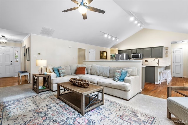 living room with visible vents, track lighting, ceiling fan, light wood-style floors, and high vaulted ceiling