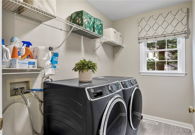 laundry room featuring visible vents, baseboards, washer and clothes dryer, laundry area, and wood finished floors