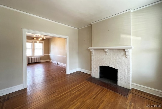 unfurnished living room featuring radiator heating unit, wood-type flooring, crown molding, baseboards, and a brick fireplace