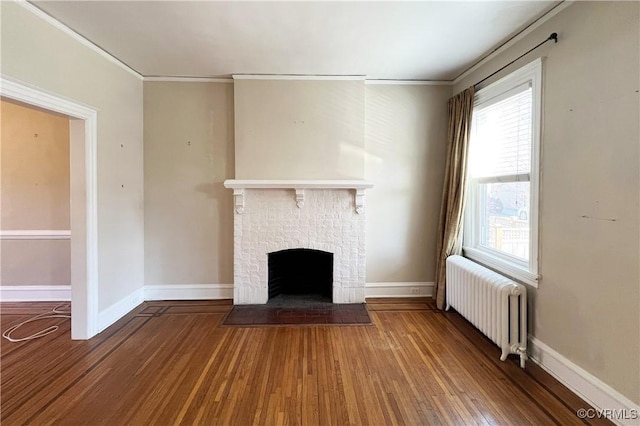 unfurnished living room with wood finished floors, radiator, a fireplace, and ornamental molding