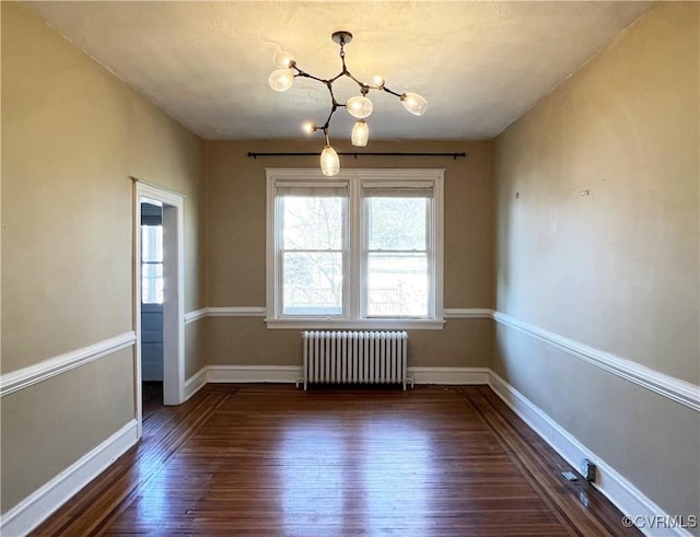 unfurnished dining area featuring baseboards, a notable chandelier, dark wood finished floors, and radiator heating unit