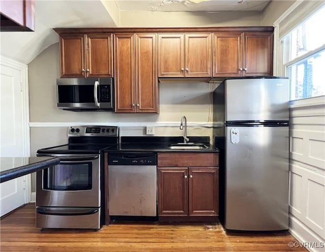 kitchen featuring dark countertops, light wood-style flooring, appliances with stainless steel finishes, and a sink