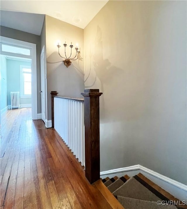 hall featuring radiator, an upstairs landing, baseboards, and wood-type flooring