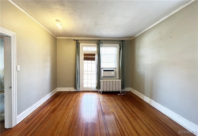 spare room with baseboards, radiator, dark wood finished floors, and crown molding