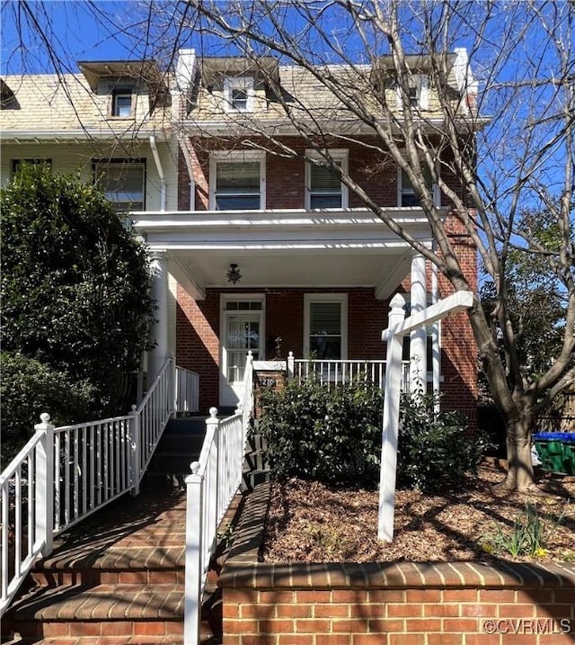 view of front of home with a porch and brick siding