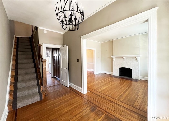 interior space with a brick fireplace, crown molding, baseboards, and wood finished floors