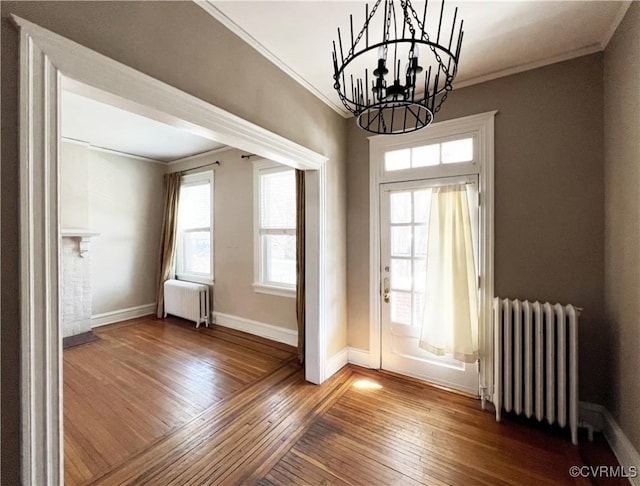 entryway with hardwood / wood-style floors, crown molding, radiator heating unit, and baseboards