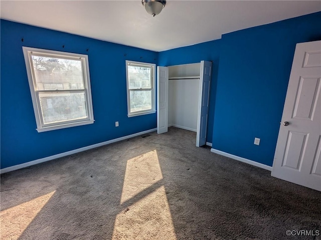 unfurnished bedroom featuring baseboards, carpet floors, a closet, and visible vents