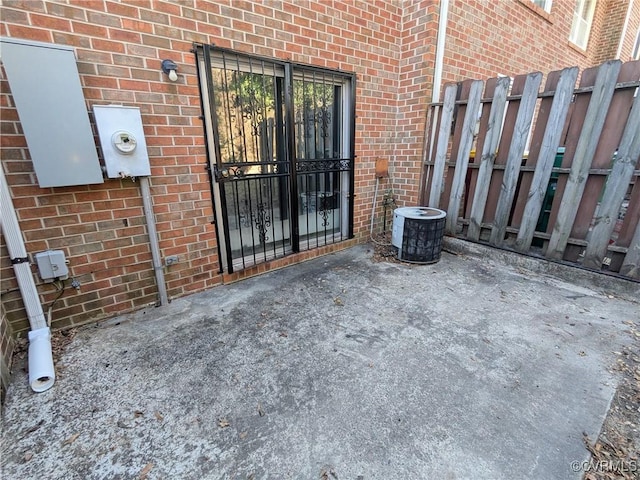 property entrance with brick siding, cooling unit, and fence