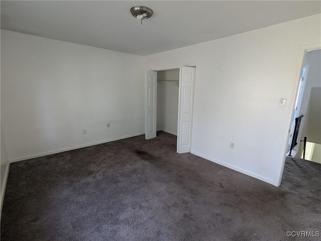 unfurnished bedroom with a closet, baseboards, and dark carpet