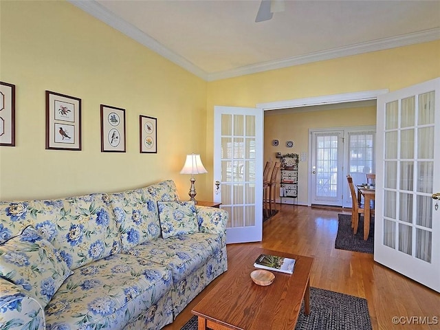 living area with a ceiling fan, crown molding, wood finished floors, and french doors