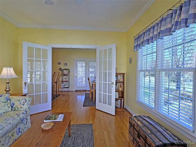 interior space with french doors, wood finished floors, baseboards, and ornamental molding