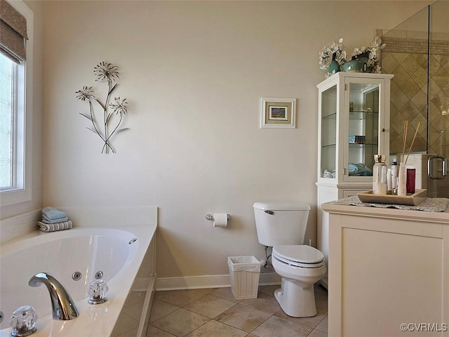 bathroom featuring tile patterned floors, a jetted tub, toilet, and a wealth of natural light