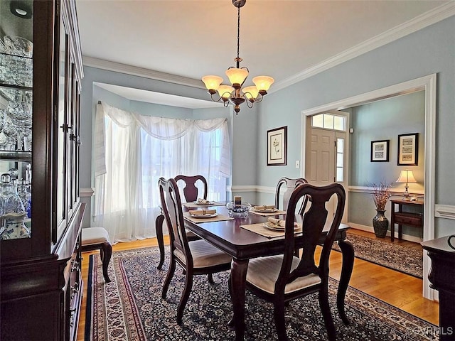 dining room with ornamental molding, baseboards, an inviting chandelier, and wood finished floors