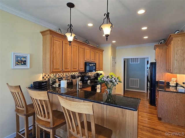 kitchen with visible vents, backsplash, ornamental molding, a peninsula, and black appliances