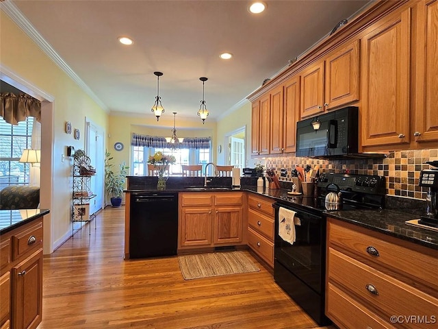 kitchen with a sink, brown cabinets, black appliances, and a peninsula