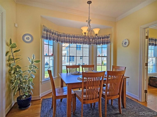 dining room with a chandelier, crown molding, baseboards, and wood finished floors