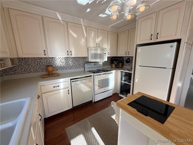 kitchen with tasteful backsplash, light countertops, a notable chandelier, white appliances, and a sink