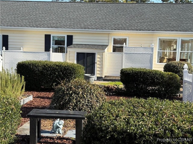 entrance to property featuring roof with shingles