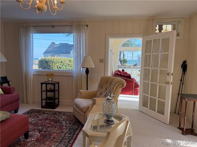 carpeted living room featuring wooden walls, a healthy amount of sunlight, and a chandelier